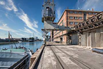 Fototapeta na wymiar Port facility with crane and cargo ship next to a warehouse