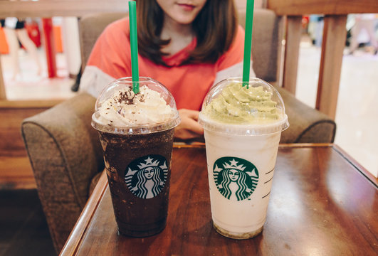 Chiang Rai, Thailand : June-07-2018 : Woman relaxing her coffee break with couple cup of Starbucks frappuccino drink in Starbucks coffee shop.