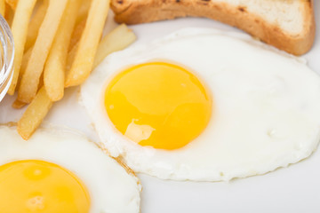 Fragmnet of breakfast with eggs and french fries.