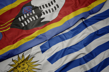 waving colorful flag of uruguay and national flag of swaziland.