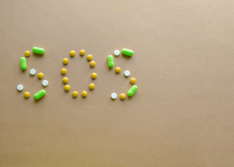 Inscription SOS of tablets on a light background. The concept of disease
