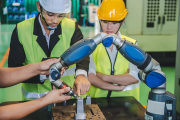 Asian male ,female engineer factory inspection with robot ai machine assist production engineer in industry we wears helmet female working metalwork control in industrial In a plastic factory for car
