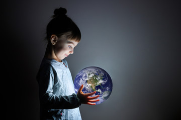 little cute girl holding a luminous planet Earth in her hands. Earth day. Elements of this image furnished by NASA.