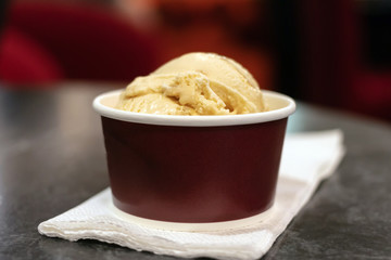 Salted caramel flavor ice-cream in take away cup on table.