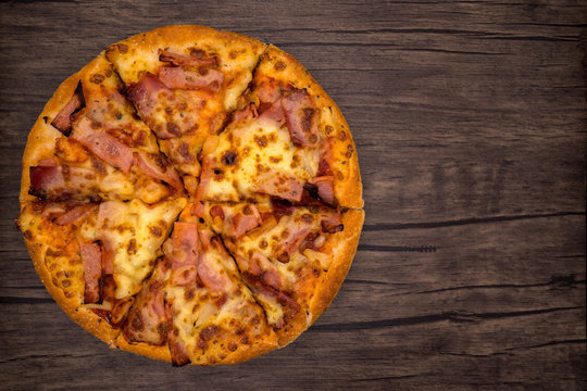 Top view, pizza on dark wooden background.