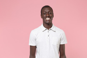 Smiling young african american man guy in white polo shirt posing isolated on pastel pink...