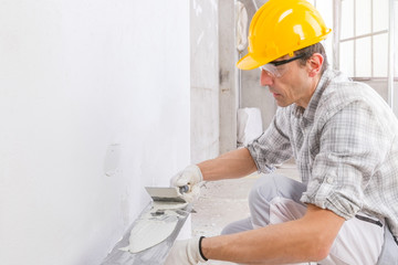 Builder using a trowel to add plaster to a wall