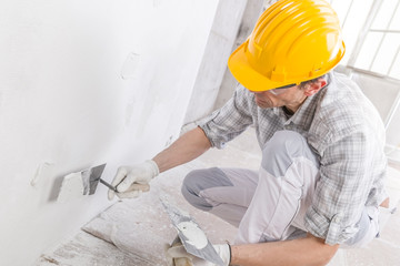 Builder using a trowel to add plaster to a wall