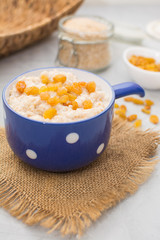 Wheat porridge with raisins in a blue ceramic cup on a napkin. Wheat porridge for breakfast. Vegetarian breakfast.