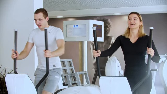Modern gym - sportsman and sportswoman doing morning exercises in the gym and laughing