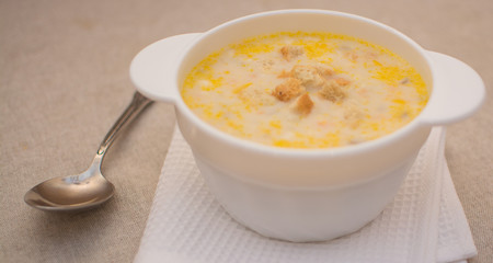 Puree soup with cheese in a white ceramic bowl on a white napkin.