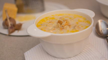 Puree soup with cheese in a white ceramic bowl on a white napkin.