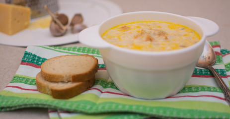Puree soup with cheese in a white ceramic bowl on a colored napkin.