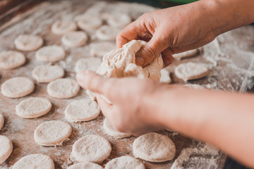 Woman in the kitchen prepares dumplings for breakfast, Ukrainian folk dish.