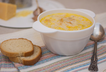 Puree soup with cheese in a white ceramic bowl on a colored napkin.