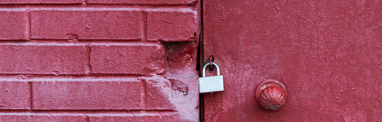 A silver padlock locks the old doors securely. Close- up view.