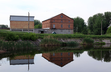 Fototapeta na wymiar Large brick building near the lake. Reflection in water.