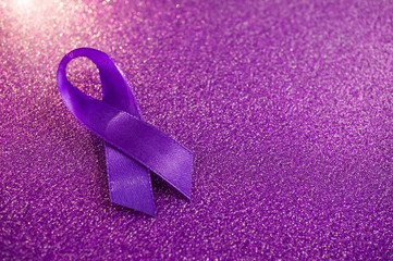 The purple ribbon is shot close-up on a sparkling violet background. Concept of epilepsy awareness.