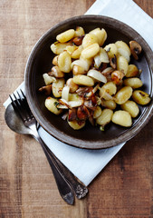 Gnocchi with onion and mushrooms. Rustic wooden background. Top view.