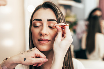 Make up artist doing professional make up of beautiful young woman.