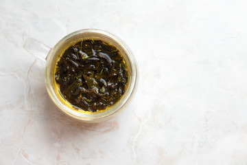 Brewing herbal tea in glass mug on marble table, top view and copy space