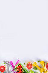 Fitness and healthy food lifestyle concept. Dumbbells, diet fruit and vegetable lunch box, water and jump rope on white background. Flatlay image, top view copy space