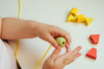 Child putting beads on a string. Bead stringing activity. Fine motor skills development. Lacing,...