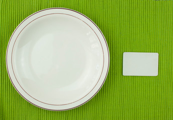 Ceramic plate with empty label on green tablecloth