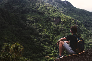 Young man resting on top of the mountain and looking at breathtaking view