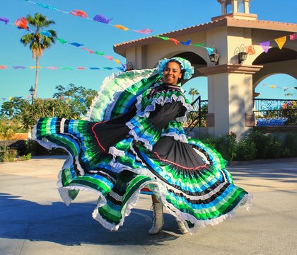 Elegante bailarina tradicional mexicana con vestido turquesa interpretando danza cultural en un festival al aire libre
