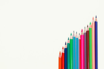 Different colored pencil crayons arranged in a row on an isolated white background