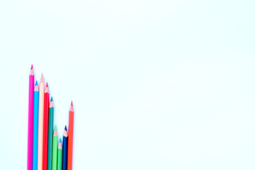 Eight different colored pencil crayons gathered in a wave saved row on a white background