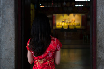 Chinese woman wearing traditional Chinese dress praying in Chinese shrine for Chinese new year luck