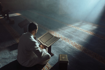 Young Muslim Guy Reading The Koran - obrazy, fototapety, plakaty