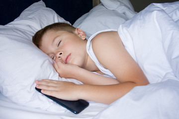 Obraz na płótnie Canvas Sleeping teenager boy holding his smartphone