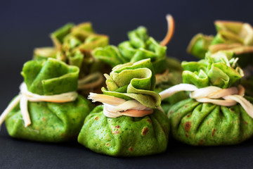 Naklejka premium Spinach pancakes with meat filling on dark background.