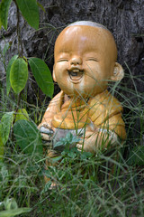 Fototapeta na wymiar The figurine of cheerful boy in garden of buddhist monastery.