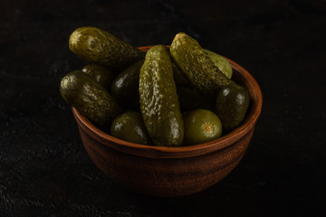 Cucumbers in a clay bowl on a dark concrete background
