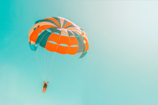 Parachute parasailing of tourists on a sandy beach Sunny weather against the background of clear sea and ocean.The wind blows up the canopy of the parachute against a clear blue sky with clouds