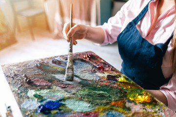 girl holds a brush near the palette
