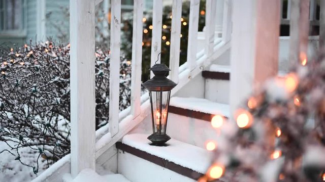 lantern on steps in front of home with snow falling - Christmas spirit concept