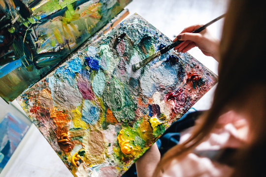 girl lowers a brush and a palette with paint