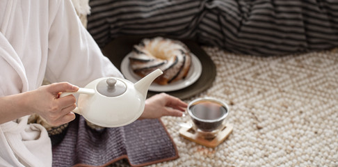 Hands of a young woman pour tea from a teapot.