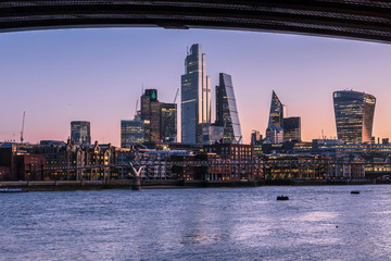 Sunrise view of London skyline and skyscrapers, from across the River Thames, framed by Blackfriars Bridge