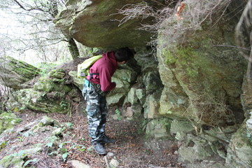 young unknown caucasian hiker finds in a forest on the Gothic Line of the Apuan Alps a cave used as a bunker in the second world war