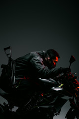 Fototapeta na wymiar profile of armed mixed race cyberpunk player in mask riding motorcycle on grey