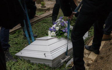 Raasiku / Estonia - January 02 2020: Funeral ceremony in small Lutheran graveyard. Undertakers lift...