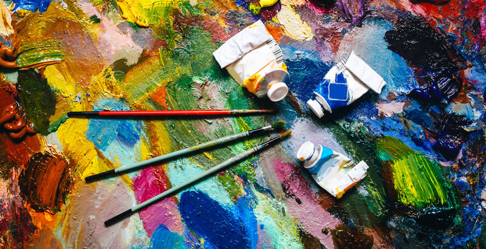 texture of oil paints on a palette with brushes and empty tubes, artist concept
