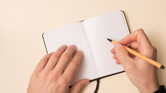 mano masculina escribiendo en una libreta peque&ntilde;a
