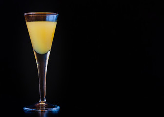 Limoncello in elegant liquor glass on dark background. Chiaroscuro. Sicilian lemon liquor, aromatic and refreshing.